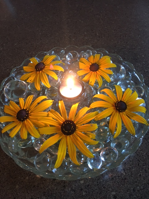 candle with daisies on clear marbles